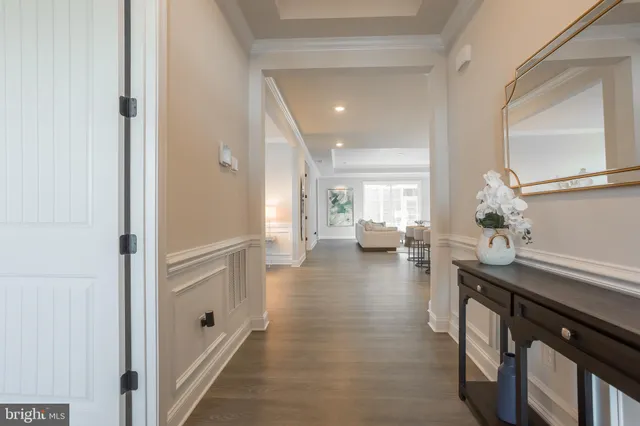 a hallway with a dining table wooden floor and a view of kitchen