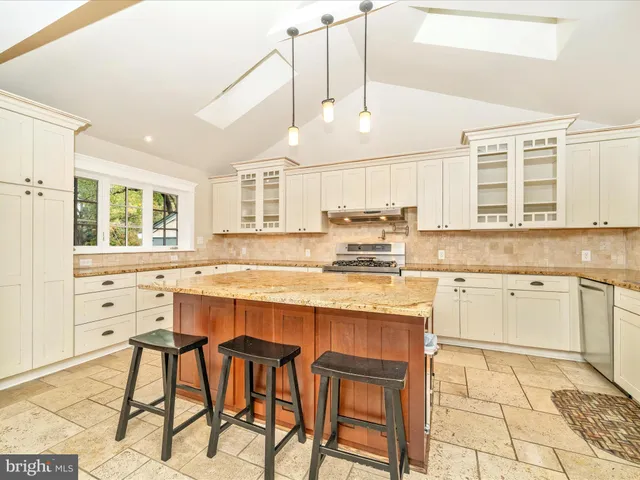a kitchen with stainless steel appliances granite countertop a stove a sink dishwasher and white cabinets with wooden floor