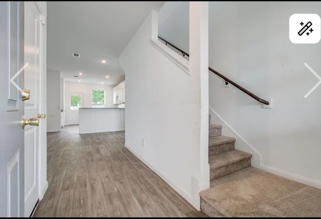 a view of a hallway with wooden floor and staircase