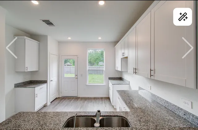 a view of kitchen with granite countertop white cabinets and black stainless steel appliances