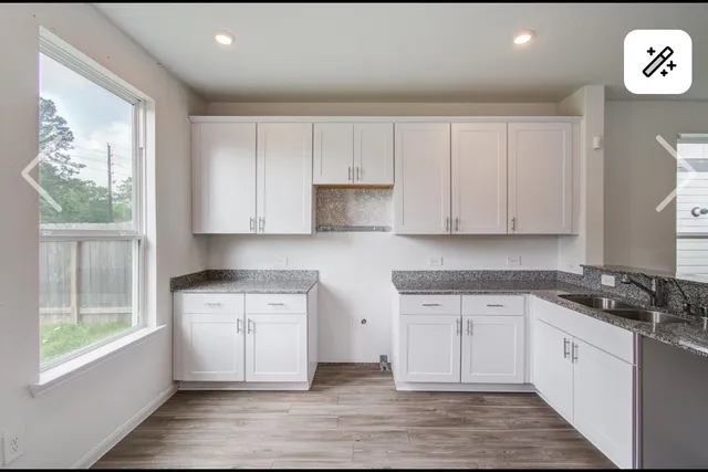 a kitchen with stainless steel appliances granite countertop a stove a sink and white cabinets with wooden floor