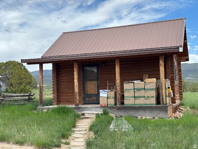 14908 North Deep Crk Road Lapoint, UT 84039 - Photo 3 of 9 Log cabin exterior featuring a brown metal roof, covered front porch, natural wood columns, and a rustic front door