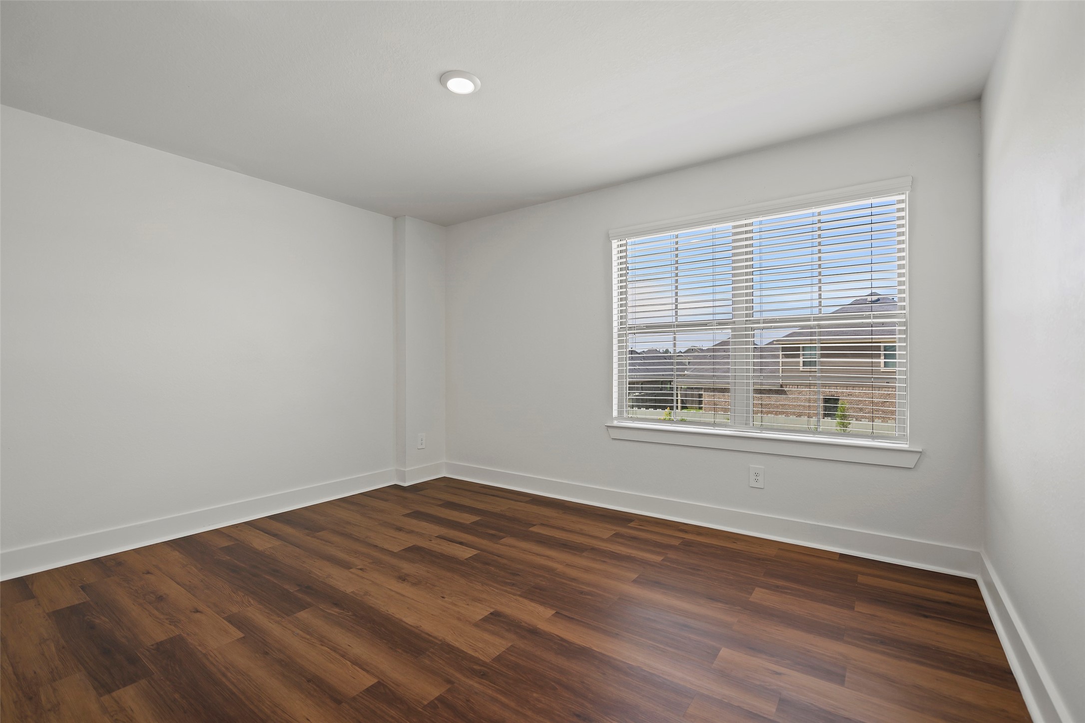 10603 Whitejacket Conroe, TX 77385 - Photo 11 of 42 The second bedroom features sleek wood flooring, a large window with blinds offering natural light, and neutral walls, creating a spacious and inviting atmosphere.