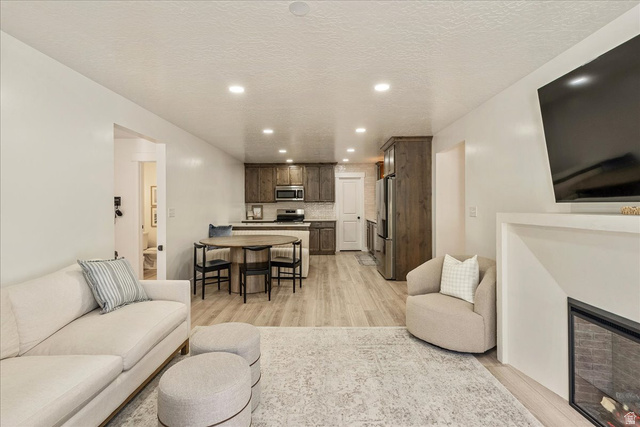 3916 South Sage Wood Avenue Mapleton, UT 84664 - Photo 9 of 33 Open-concept living space featuring wood-finish flooring, recessed lighting, and a built-in fireplace
