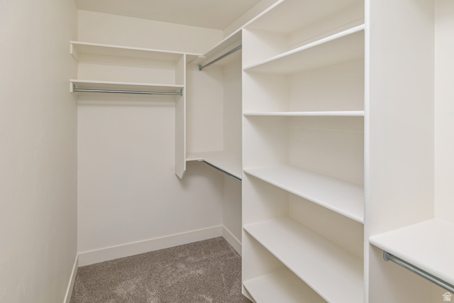 612 North 400 West Logan, UT 84321 - Photo 19 of 27 Walk-in closet featuring built-in shelving, multiple hanging rods, and neutral carpet flooring