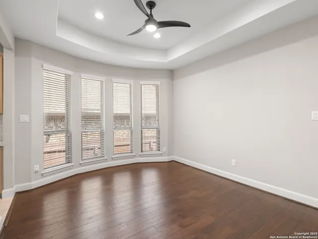 an empty room with wooden floor and windows with curtains
