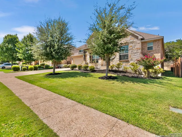 a front view of a house with a garden and trees