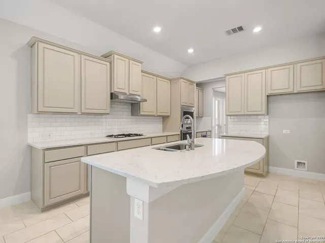 a kitchen with stainless steel appliances granite countertop a sink a stove and white cabinets