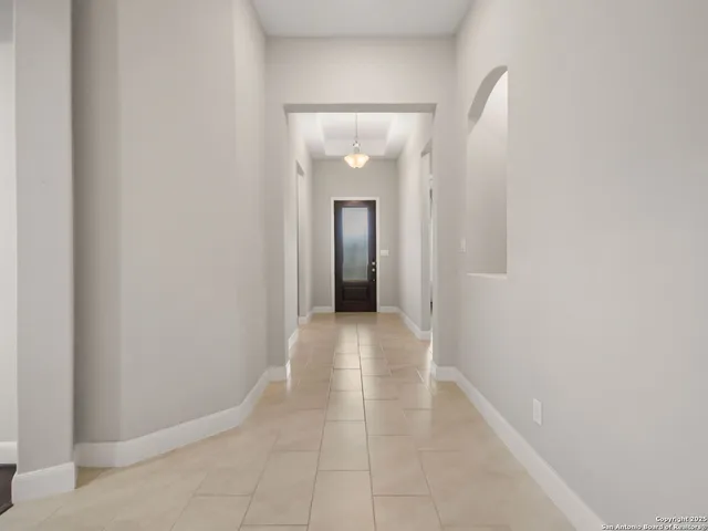 a view of a hallway with wooden floor and a large mirror