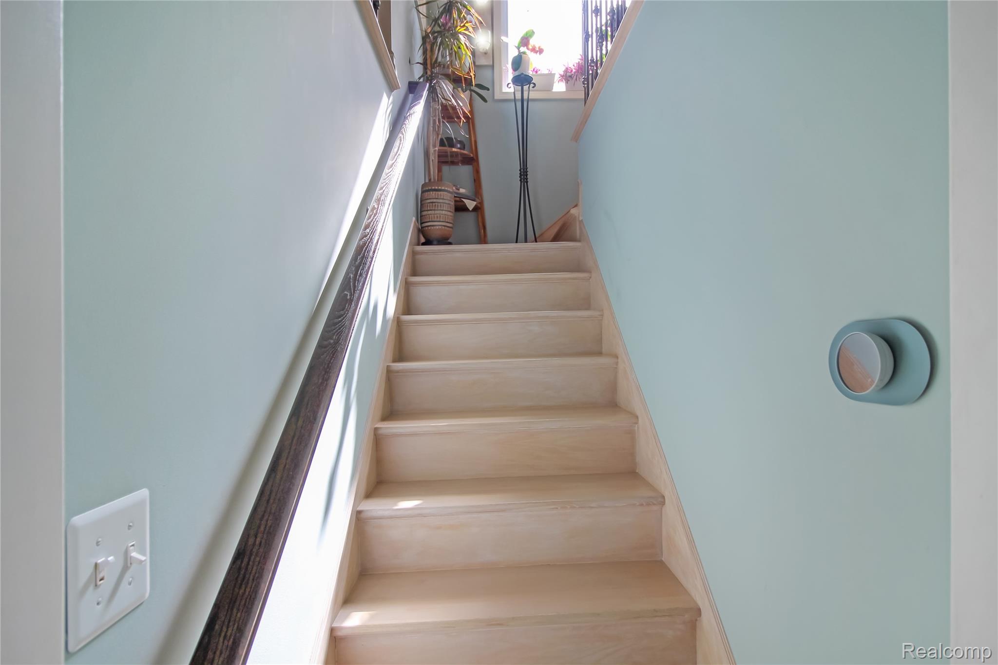 5953 Cooper Street Taylor, MI 48180 - Photo 26 of 33 Natural wood-finish staircase with a dark wood-finish handrail, light blue wall paint, and a modern circular thermostat