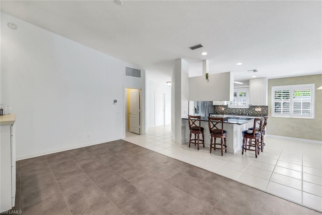3025 Futuna Lane Naples, FL 34119 - Photo 15 of 46 Kitchen with a breakfast bar, white cabinets, backsplash, stainless steel refrigerator with ice dispenser, and light tile patterned floors
