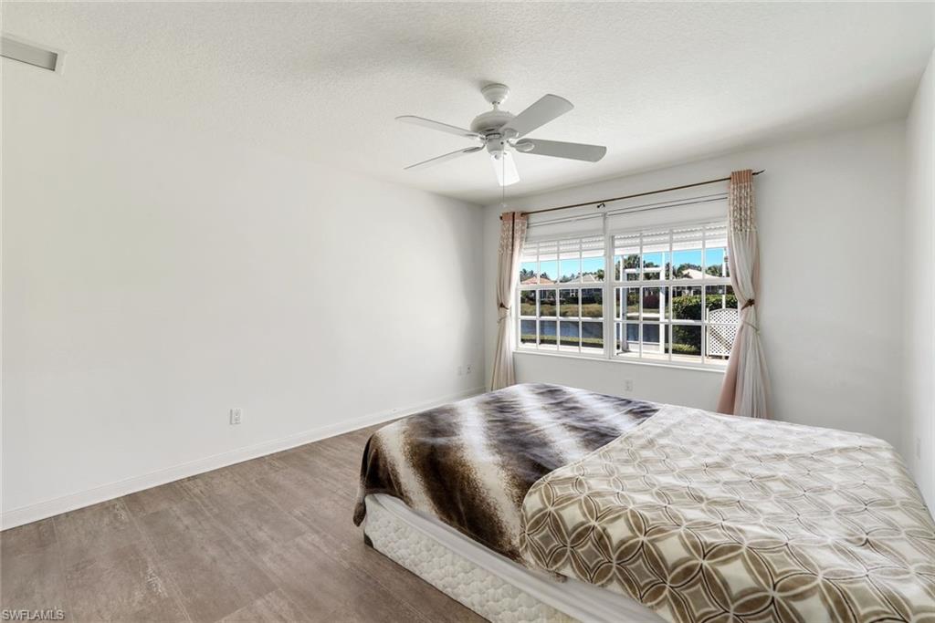 3025 Futuna Lane Naples, FL 34119 - Photo 21 of 46 Bedroom featuring wood finished floors, ceiling fan, and a textured ceiling