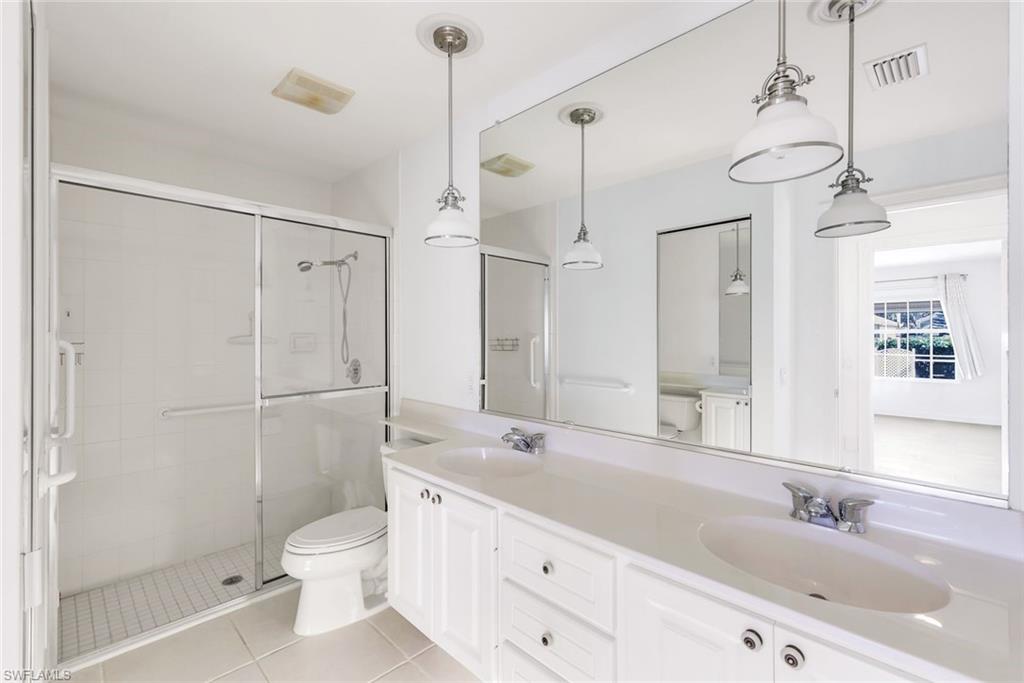 3025 Futuna Lane Naples, FL 34119 - Photo 22 of 46 Bathroom featuring double vanity, a stall shower, and light tile patterned floors