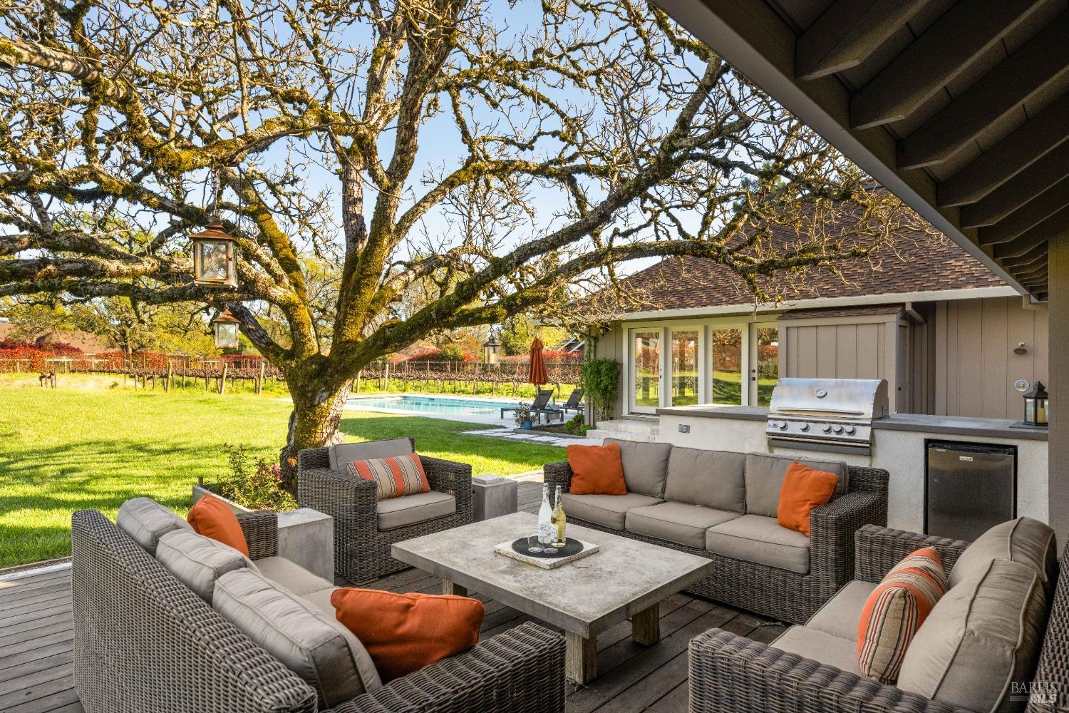 a view of a patio with couches fire pit and a large tree