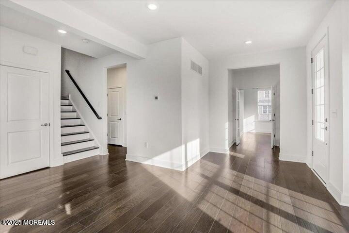 179 Woolley Court, Unit 1 Asbury Park, NJ 07712 - Photo 3 of 24 a view of an empty room with wooden floor and stairs