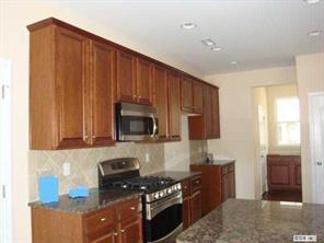 1724 Ridgehaven Road, Unit 220 Waxhaw, NC 28173 - Photo 5 of 16 a kitchen with granite countertop a stove top oven microwave and cabinets