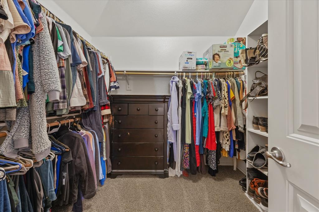 409 Harding Lane Lavon, TX 75166 - Photo 14 of 34 Spacious walk-in closet featuring built-in hanging rods, integrated shelving, and a central dresser with multiple drawers