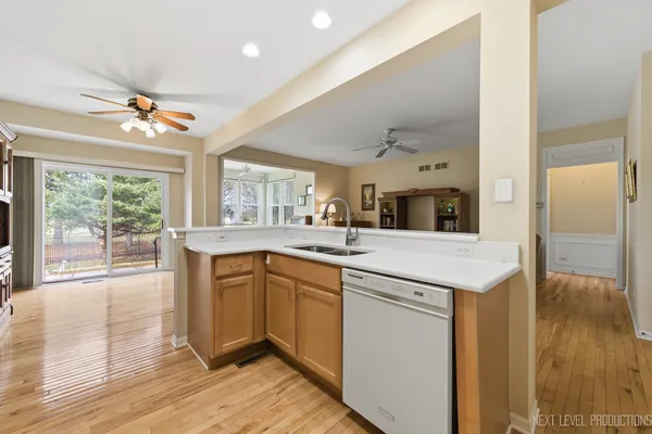 a large kitchen with a stove a sink dishwasher and a refrigerator with wooden floor
