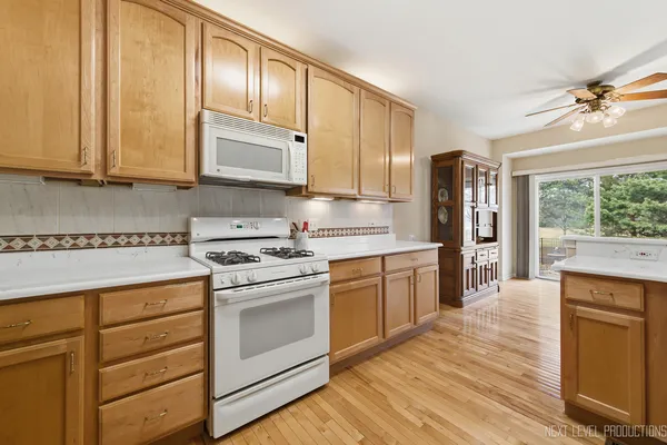 a kitchen with stainless steel appliances granite countertop a stove a sink and white cabinets with wooden floors