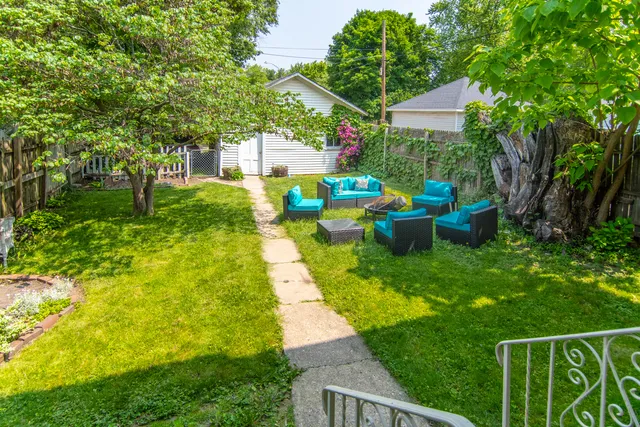 a view of backyard with table and chairs and a large tree