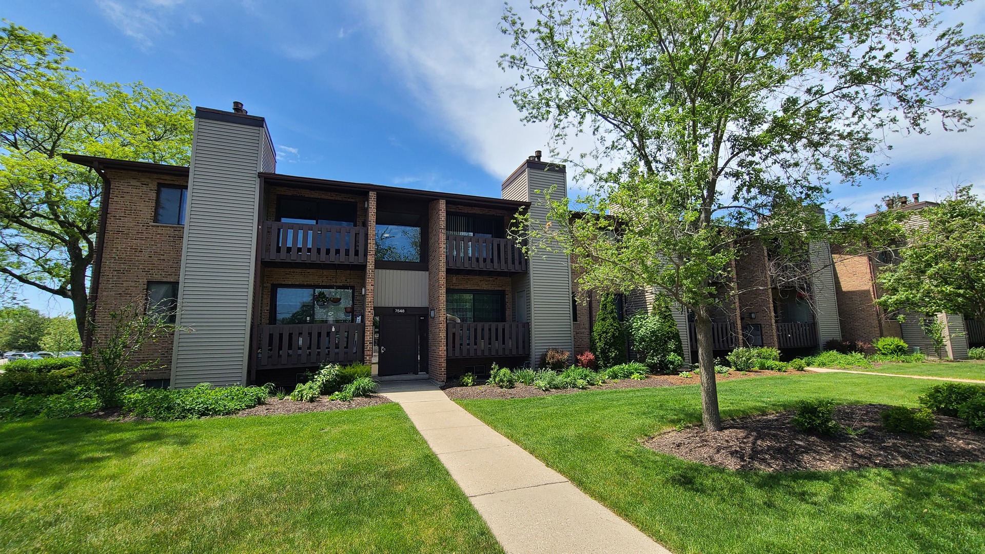 a view of a brick house with a yard and large trees