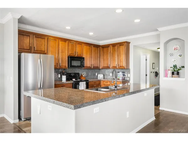 a kitchen with stainless steel appliances granite countertop a refrigerator a stove top oven a sink and dishwasher