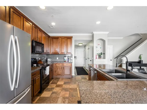 a kitchen with stainless steel appliances kitchen island granite countertop a refrigerator a sink a stove with cabinets