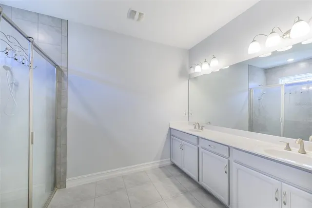 a spacious bathroom with a shower a sink and mirror