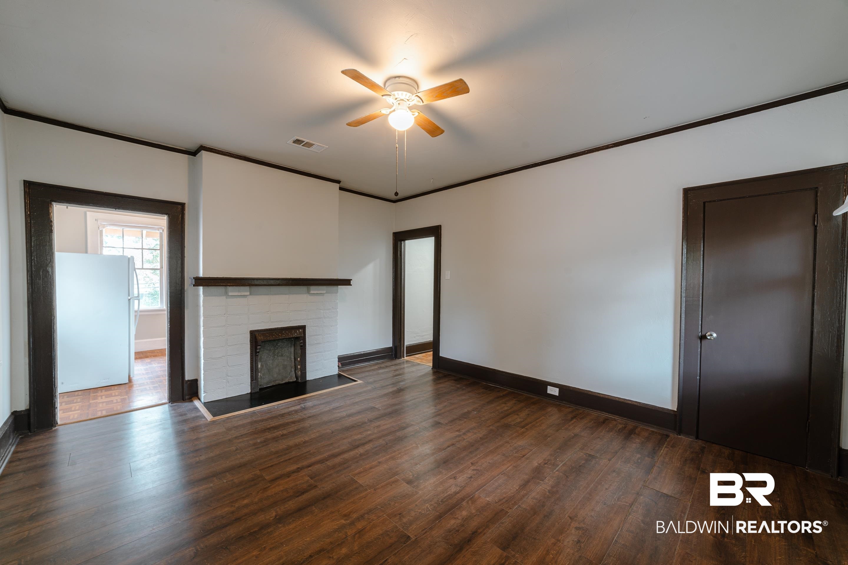 312 1st Street Mobile, AL 36611 - Photo 5 of 29 Unfurnished living room featuring crown molding, a brick fireplace, dark hardwood / wood-style floors, and ceiling fan
