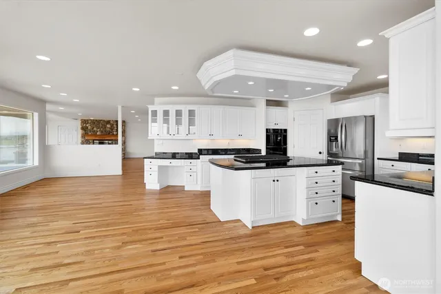a kitchen with stainless steel appliances granite countertop a stove top oven a sink and white cabinets