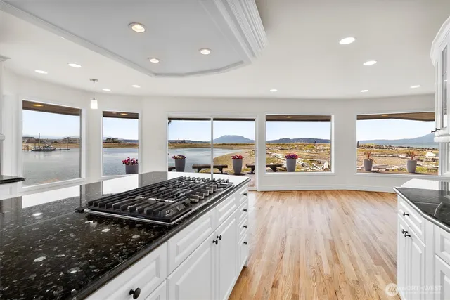 a kitchen with a stove a sink and white cabinets with wooden floor