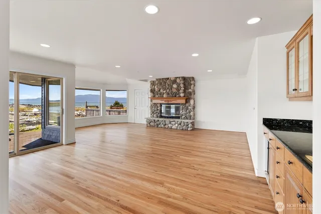 an empty room with wooden floor and a kitchen