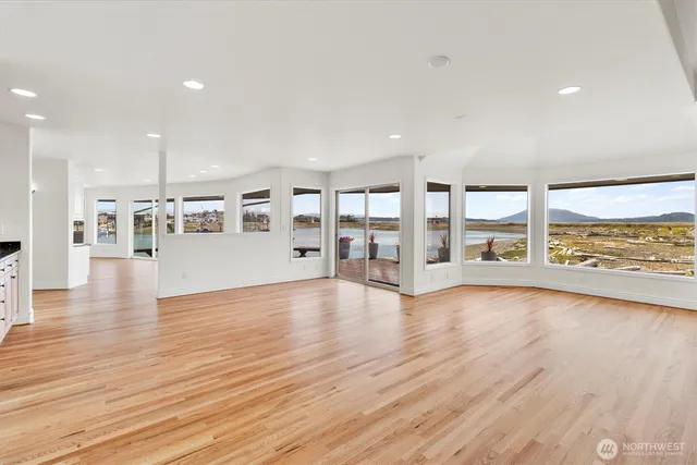 a view of an empty room with wooden floor and a floor to ceiling window