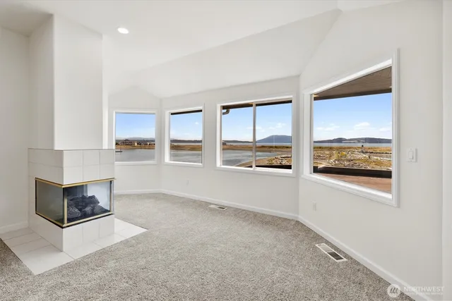 an empty room with windows fireplace and view