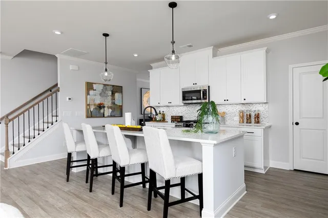 a kitchen with stainless steel appliances kitchen island granite countertop a dining table chairs and white cabinets
