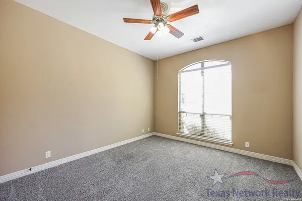an empty room with windows and fan