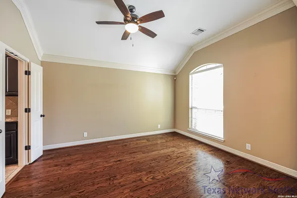 an empty room with wooden floor fan and windows