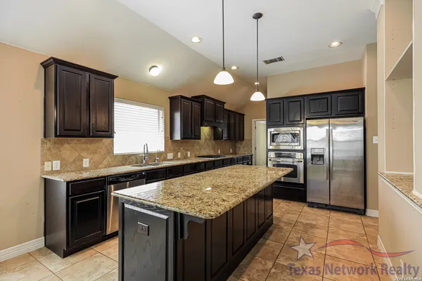a kitchen with granite countertop kitchen island a refrigerator a oven and a sink