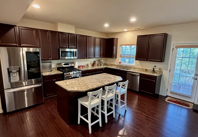 a kitchen with stainless steel appliances wooden floor sink and wooden cabinets