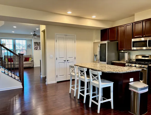 a kitchen with stainless steel appliances kitchen island granite countertop a table chairs and a refrigerator