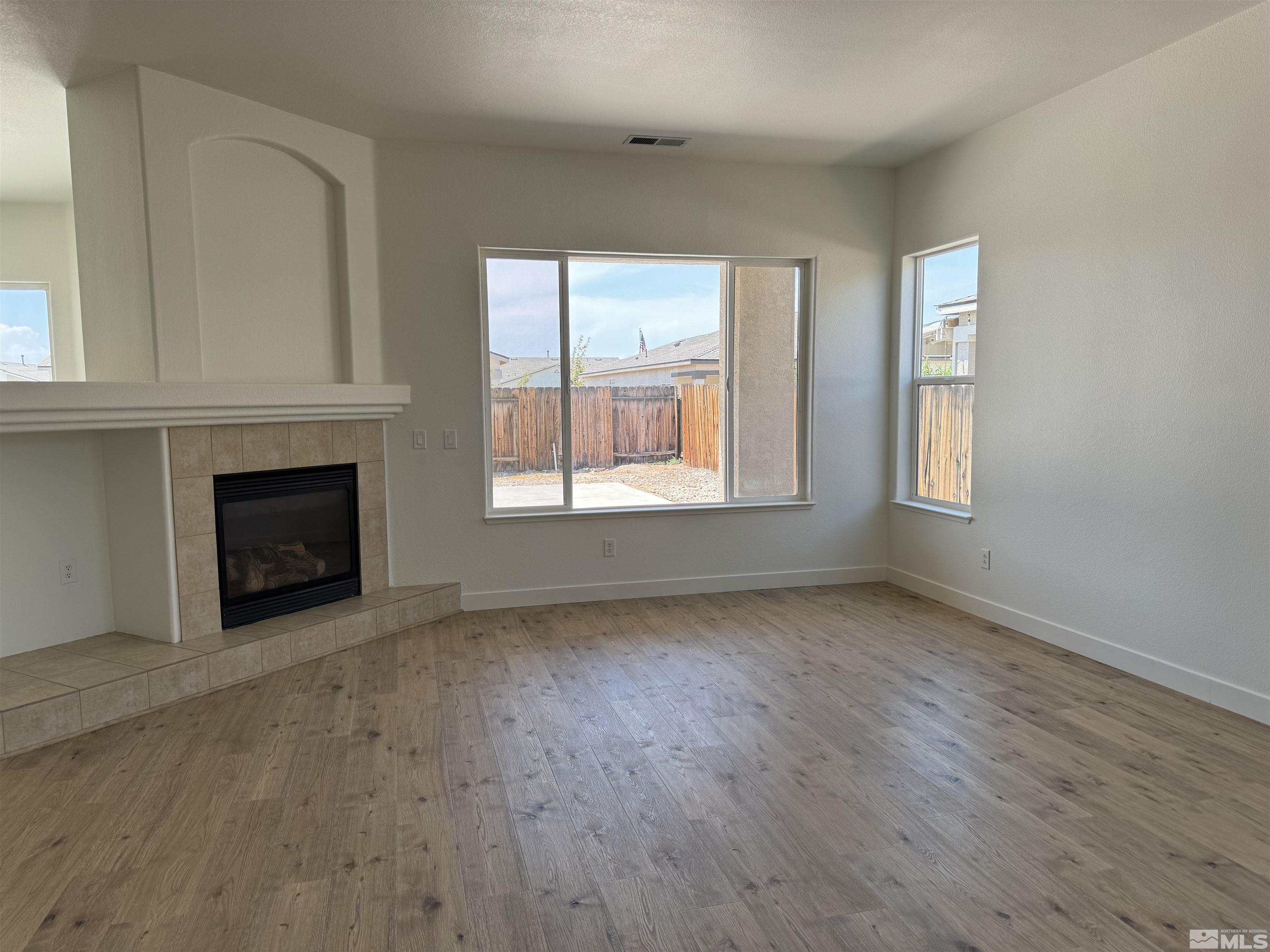 405 Sapphire Way Fallon, NV 89406 - Photo 4 of 30 an empty room with wooden floor fireplace and windows