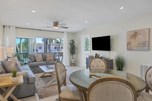 a living room with stainless steel appliances furniture a dining table and kitchen view
