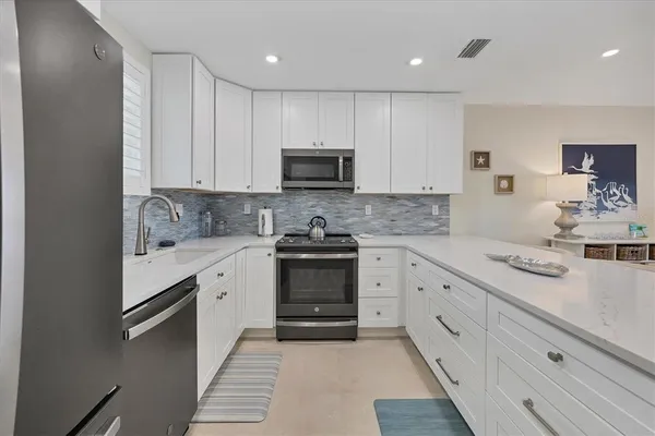 a kitchen with stainless steel appliances granite countertop white cabinets a window and a sink