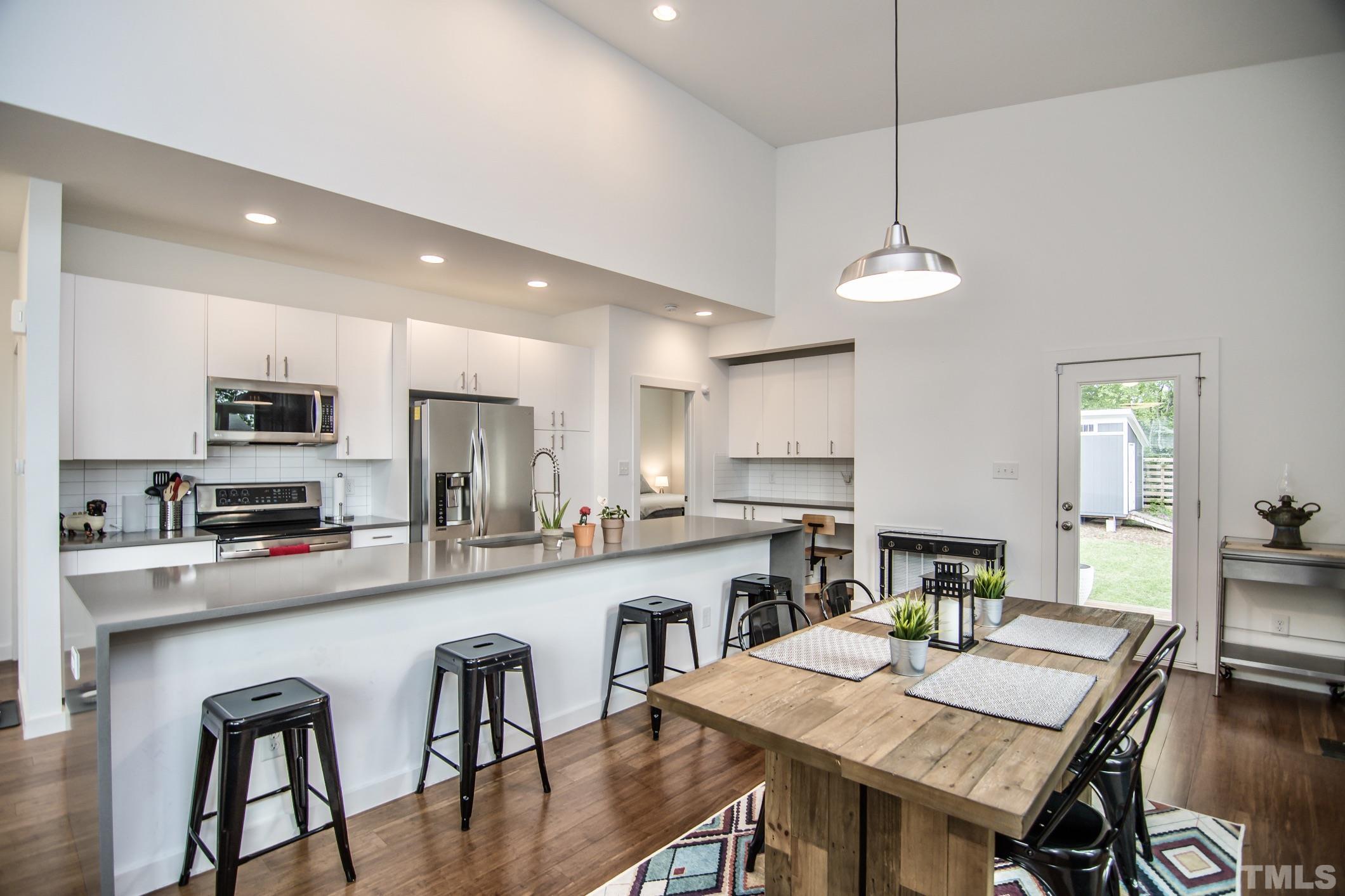 1309 South East Street Raleigh, NC 27601 - Photo 11 of 29 a kitchen with stainless steel appliances granite countertop a stove a refrigerator a kitchen island a dining table and chairs