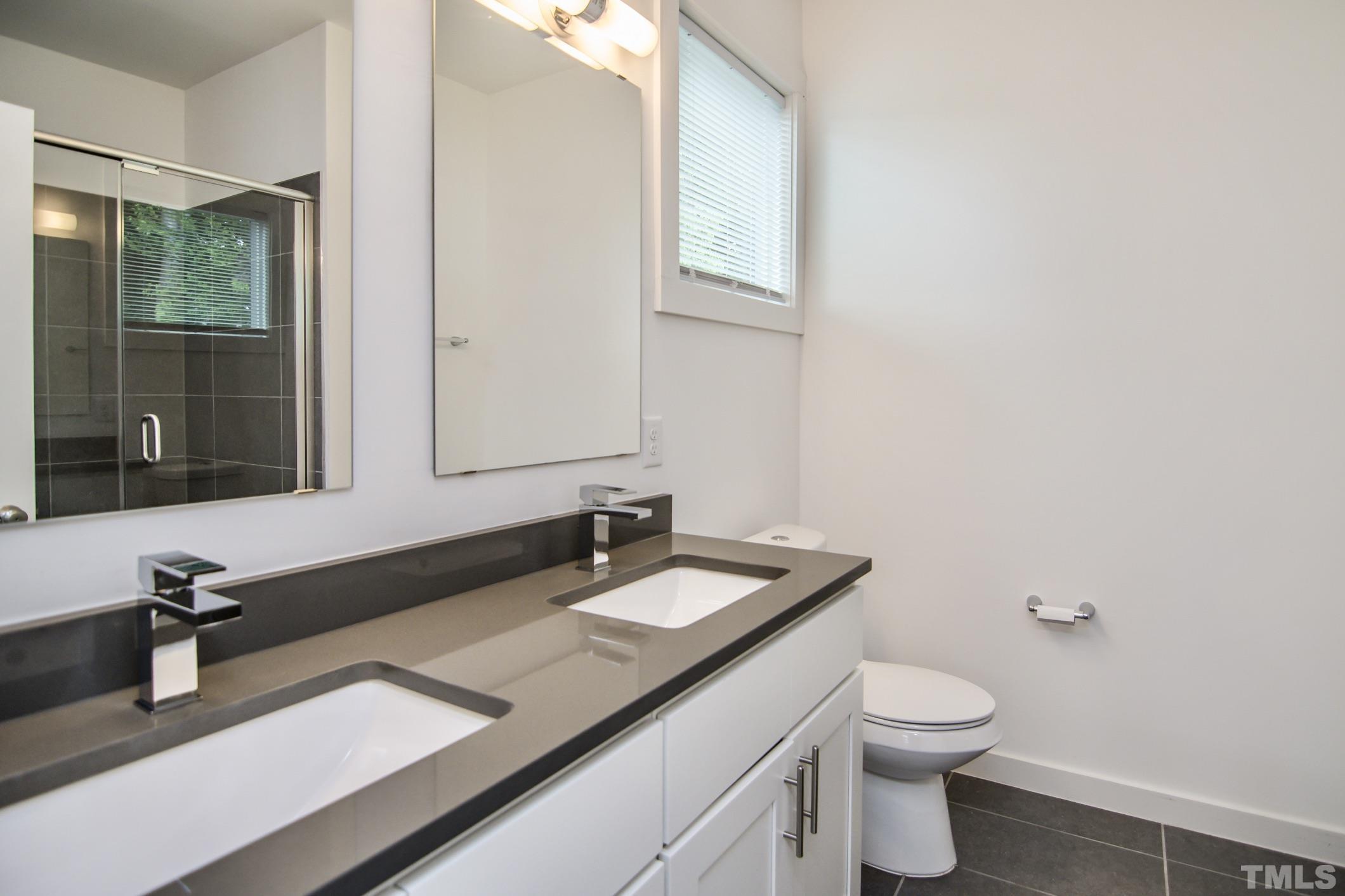 1309 South East Street Raleigh, NC 27601 - Photo 16 of 29 a bathroom with a granite countertop sink a toilet and mirror