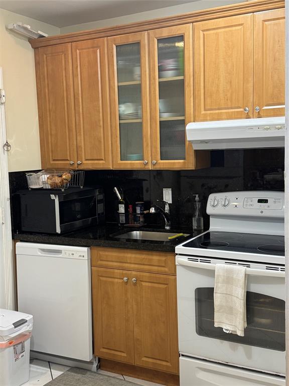 2220 Northeast 68th Street, Unit 1031 Fort Lauderdale, FL 33308 - Photo 12 of 12 a kitchen with granite countertop a stove a sink and a microwave