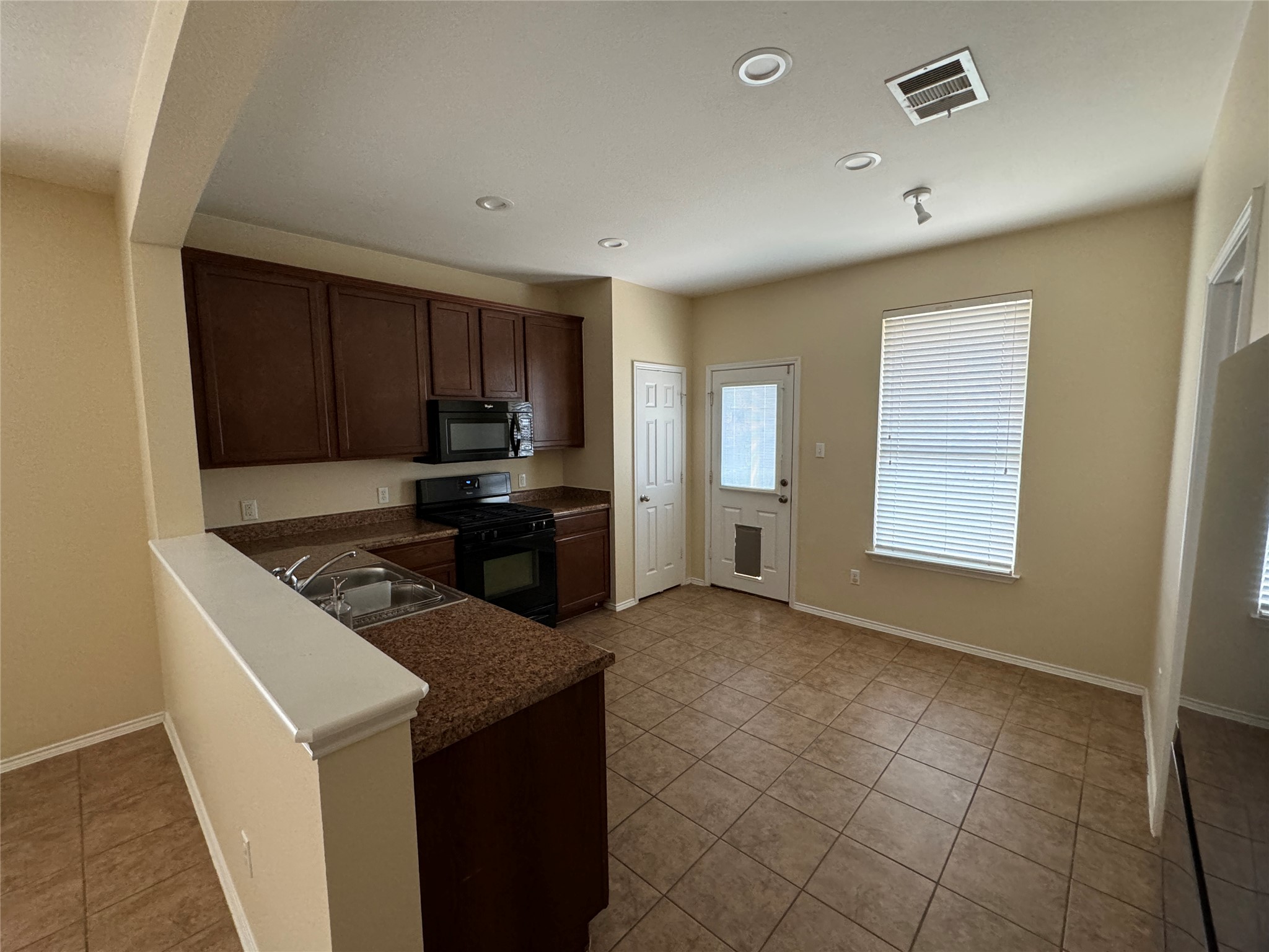 147 Pine Arbol Buda, TX 78610 - Photo 3 of 7 Kitchen featuring dark wood finish cabinetry, black appliances, recessed lighting, dark countertops, and a peninsula