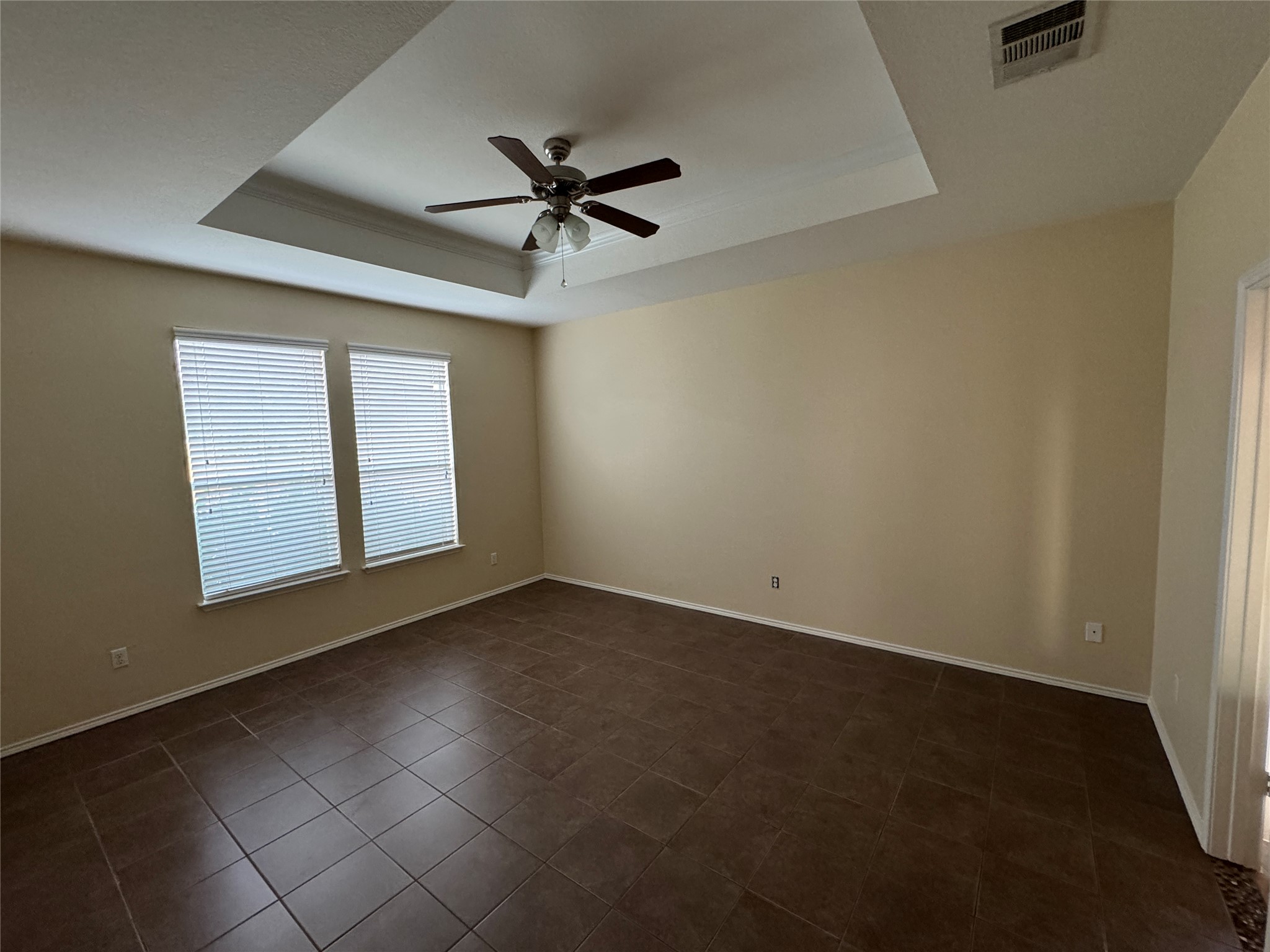 147 Pine Arbol Buda, TX 78610 - Photo 4 of 7 Master bedroom featuring a ceiling fan, dark tile patterned flooring, and a raised ceiling