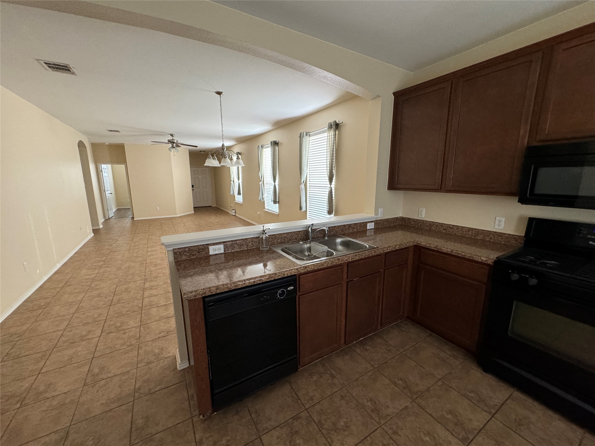 147 Pine Arbol Buda, TX 78610 - Photo 7 of 7 Kitchen featuring black appliances, a peninsula, dark wood finish cabinetry, open floor plan, and a ceiling fan