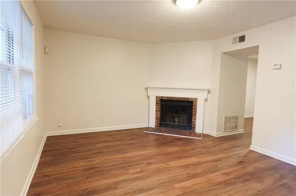 a view of empty room with wooden floor and fireplace